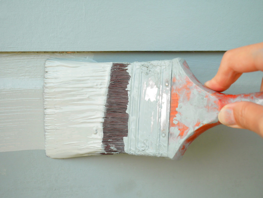 hand with painting brush on wooden surface