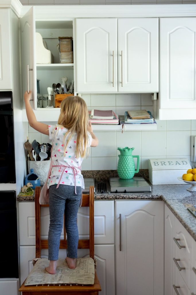 girl accessing kitchen cabinet shelf